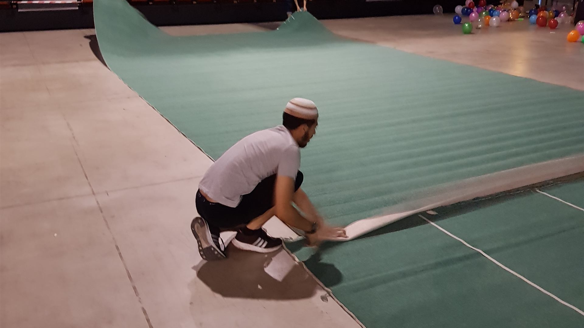 Un bénévole déroule les tapis dans le hall